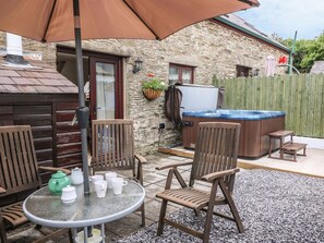 Eine Terrasse mit rundem Tisch, Stühlen, einem Whirlpool und einer Steinmauer.
