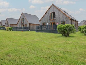 File di chalet in legno con balconi, un prato verde e cielo sereno.
