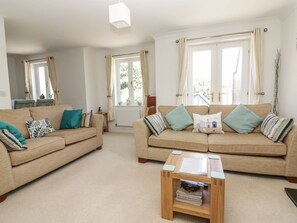 A living room with two beige sofas, a coffee table, and large windows with curtains. - Strawberry Cottage, Penryn (Penryn)