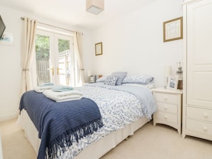 A bedroom with a bed, bedside table, and wardrobe. - Strawberry Cottage, Penryn (Penryn)