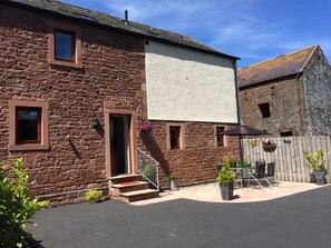 A stone building with a large whiteboard, outdoor seating, and a wooden fence.
