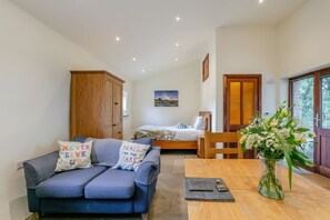 Ein Zimmer mit einem blauen Sofa, einem Holztisch, einem Bett und einem Holzschrank.