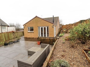 A residential backyard with a brick house, a patio area, and a garden with various plants. - Blakelaw Court, Alnwick (Alnwick)
