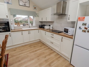 A modern kitchen with white cabinets, a wooden countertop, a built-in oven, a microwave, and a refrigerator. - Blakelaw Court, Alnwick (Alnwick)