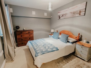 A bedroom with a bed, nightstands, a dresser, and a painting on the wall.