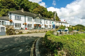 A white building with multiple windows and a stone wall, likely a hotel or inn, with a road in front and parked cars. - Fal River Cottage, Malpas, Cornwall (Truro)