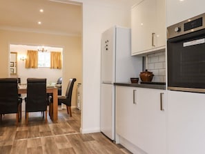 A compact kitchen with white cabinets, a refrigerator, and a microwave. - The Garden House in Whitstable (Whitstable)