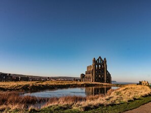 A historic building with a large central tower, a moat, and a clear sky. - The Old Mill Cottage is in Low Hawsker (Whitby)