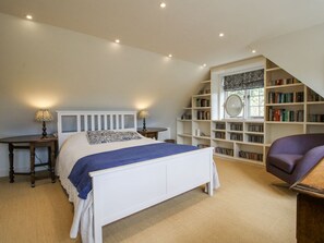 Une chambre à coucher avec un lit, des tables de chevet, une bibliothèque et une fenêtre.