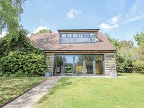 Ein zweistöckiges Haus mit großer Glasschaufassade, geneigtem Dach und gepflasterter Auffahrt.