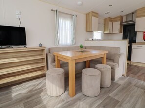 Una sala moderna con un mueble de televisión de madera, un sofá, una mesa de comedor y otomanas.