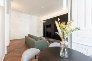 A modern living room with a sofa, a round table with a vase, and a herringbone wooden floor. - High-End 1BR Apt. with A/C & Parking Steps from Wenceslas Square by EasyBNB Premium (Prague)