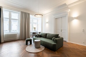 A modern living room with a green sofa, round coffee table, and a dining area with chairs and a table. - High-End 1BR Apt. with A/C & Parking Steps from Wenceslas Square by EasyBNB Premium (Prague)