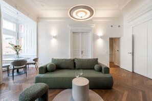 A modern living room with a green sofa, a round coffee table, and a vase of flowers on a table. - High-End 1BR Apt. with A/C & Parking Steps from Wenceslas Square by EasyBNB Premium (Prague)