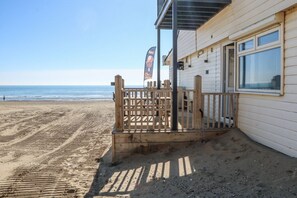 A beachside building with a wooden deck, a flag, and a view of the ocean. - Charming Sandunes 2 Retreat in Camber (Rye)