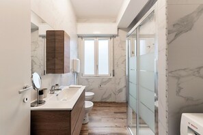 Ein modernes Badezimmer mit einem Holzbadezimmerhocker, einer Duschkabine aus Glas und einer Marmor-Spritzschutzwand.