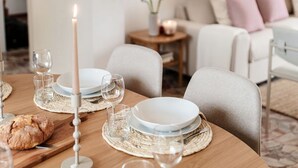A dining table set with plates, glasses, and a candle, with a loaf of bread on a cutting board. - Ruan Downtown - MyHomeinComo (Como)