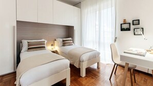 A modern bedroom with two beds, a desk, and a chair. - Ruan Downtown - MyHomeinComo (Como)