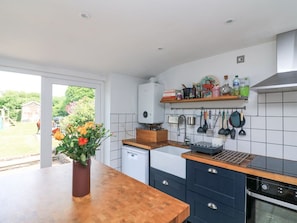 A kitchen with a wooden countertop, a built-in oven, a dishwasher, and a window with a view of greenery. - Joymead: Charming Retreat in Malborough (Kingsbridge)