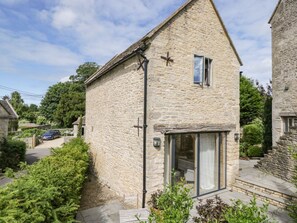 A stone house with a cross on the wall, a window, and a door with glass panels. - The Barn, Colerne, Wiltshire (Chippenham)