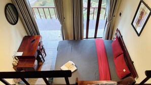 Una habitación con una cama, un aparador de madera, una ventana con cortinas y un cuadro en la pared.