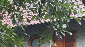 Un edificio con fachada de piedra, barandilla de balcón de madera y una ventana redonda con contraventanas.
