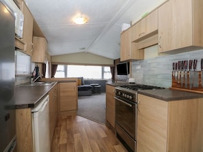 A compact kitchen with wooden cabinets, a stove, and a sink. - 90 Solent Breezes, Warsash (Southampton)