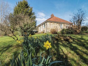 A stone building with a red-tiled roof, surrounded by a well-maintained lawn and flowering daffodils. - Low Muffles Bridge, Pickering (Pickering)