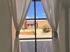 A window with white curtains, a brick building, and a paved area outside. - Charming Wabi in Gembling, Yorkshire (Driffield)