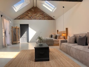 A loft-style bedroom with a sloped ceiling, skylights, a bed, a sofa, and a small table with a plant. - Charming Wabi in Gembling, Yorkshire (Driffield)