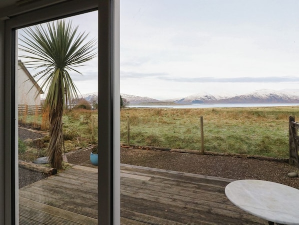 A patio with a table and a view of a grassy field and mountains.
