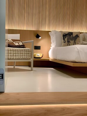 A modern bedroom with a wooden slatted ceiling, a bed with zebra-themed pillows, a bedside table with a lamp, and a chair with a patterned cushion. - Elegant apartment in the historic center of Verona (Verona)