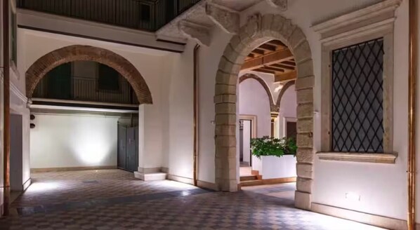 An interior corridor with stone arches, a checkered floor, and a view into another room. - Elegant apartment in the historic center of Verona (Verona)