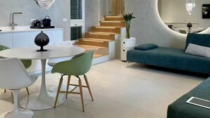 Un interior moderno con zona de comedor, sofá, escalera y cocina.