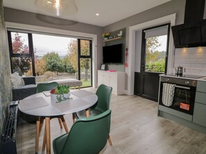 A modern kitchen with a dining area, large windows, and a view of the outdoors. - Charming Lake View House Apartment (Newry)