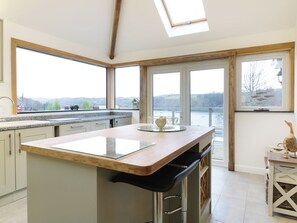 A modern kitchen with a large island, a view of a lake, and a skylight. - Treetops: A Hidden Gem in Golant (Fowey)