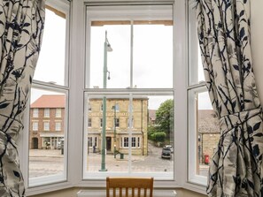 Une pièce dotée d’une grande fenêtre, d’une chaise et offrant une vue sur un bâtiment portant l’inscription « Oldenfield Hotel ».