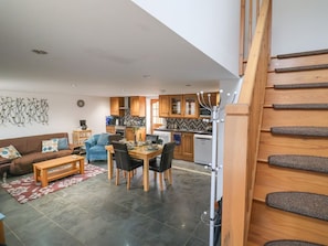Eine moderne Küche mit Holzausbau, ein Essbereich mit Tisch und Stühlen sowie eine Treppe mit Gewebestufen.