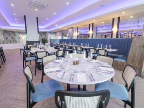 Un restaurant amb taules rodones, caires i una zona amb seients blaus.