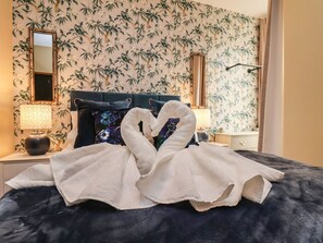 A bed with a dark blue headboard, two pillows, and a white towel.