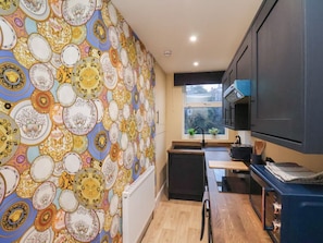 A kitchen with a patterned wall, a window, and modern appliances.