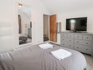 A bedroom with a bed, a television, a dresser, and a door leading to another room. - Castle Manor is in Scarborough (Scarborough)