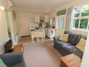A compact living space with a kitchenette, a sofa, a dining table, and a TV. - Damson Croft, Lastingham (York)