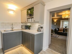 A modern kitchen with grey cabinets, a white countertop, and a built-in plant shelf. - Inglis Nook Cottage Retreat (Lochearnhead)