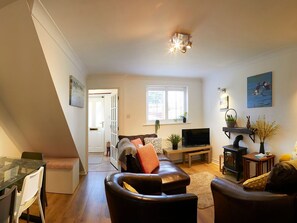 A living room with a sofa, a television, a fireplace, and a window. - Rosewood Cottage, Flamborough (Bridlington)