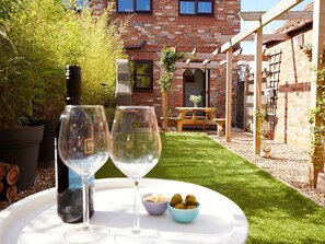 A patio with a table set for two, two wine glasses, and a bowl of olives. - Rosewood Cottage, Flamborough (Bridlington)
