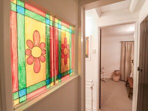 A hallway with a stained glass window featuring floral designs.