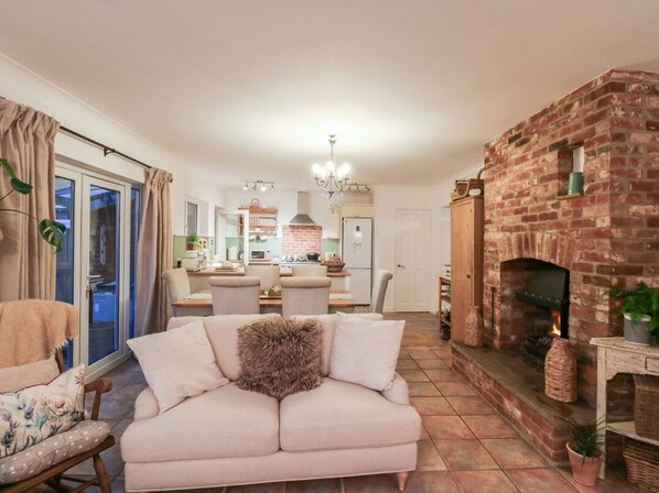 A living room with a sofa, a fireplace, and a dining area in the background.