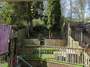 A fenced outdoor area with a wooden deck, a stone wall, and a tree. - 69 Main Street central Haworth (Keighley)