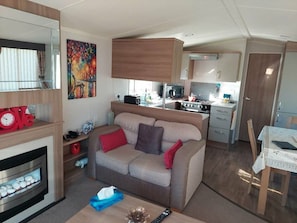 Un espacio habitable compacto con kitchenette, un sofá, una chimenea y un cuadro en la pared.